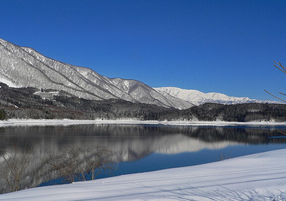 遠くに雪山が見える青木湖の風景